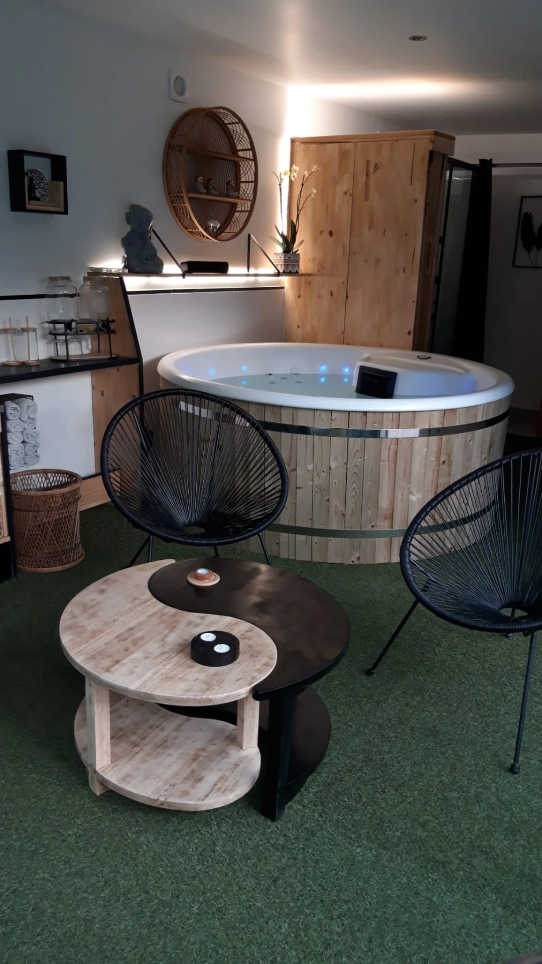 Espace balnéothérapie avec un jacuzzi rond en bois et une table en bois