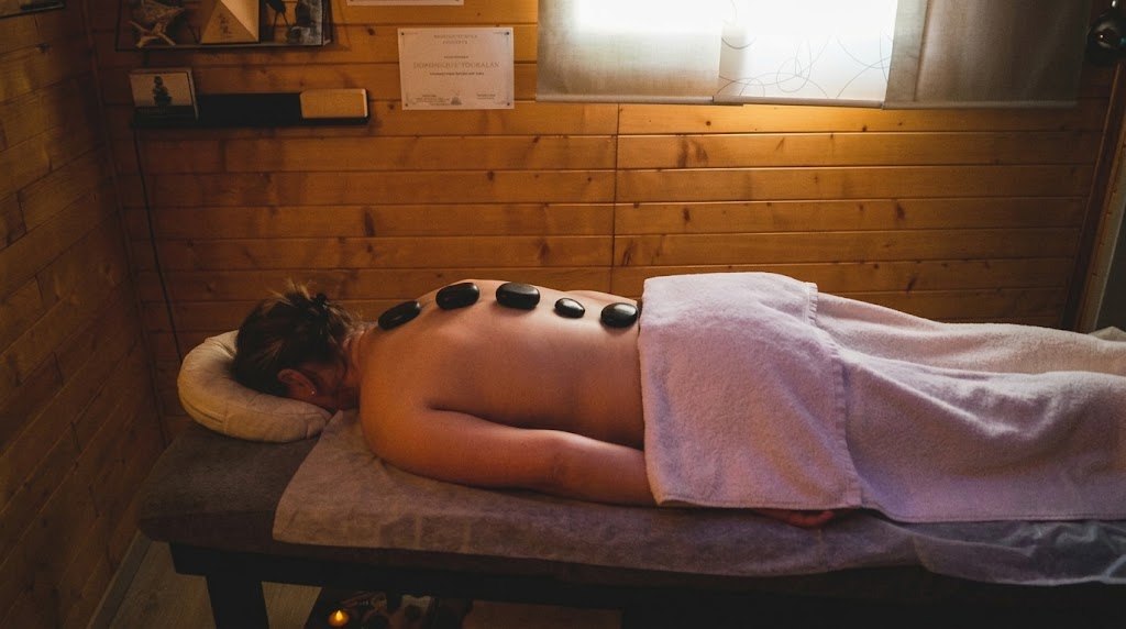 Personne recevant un massage aux pierres chaudes posées le long du dos