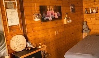 Intérieur de la cabine de massage en bois : bougies, statuette Bouddha et table de soin